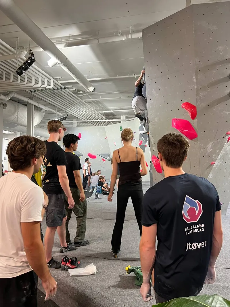 Folk på matten ved en buldrevegg med rosa tak